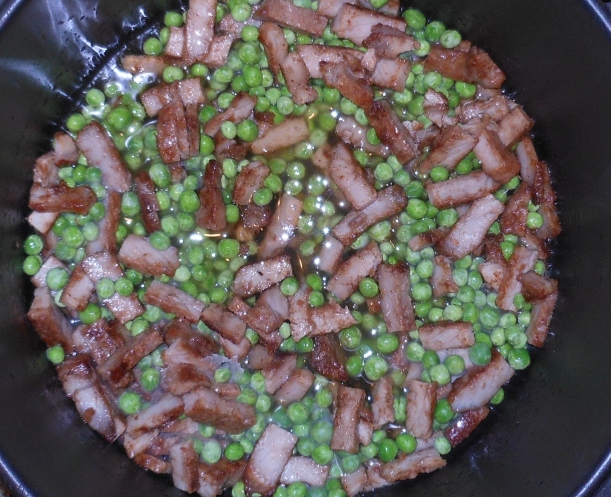 I preheated some oil on the stove.  To keep the rice from sticking, you will need more oil than you're used to using.  Then, I added the pork to the pan and cooked it for a minute.  Next, I added the peas and let them heat through.