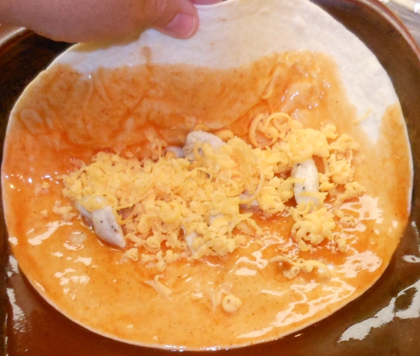 Next, I transferred the tortilla to the pan and filled it with chicken and cheddar cheese.