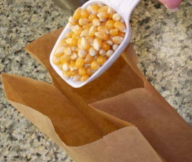 I measured about 3 tablespoons of unpopped popcorn into a plain, brown lunch bag. If you don't have a lunch bag, you can put this into a microwaveable bowl and put a plate on top to cover it.